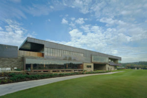 Blessings Golf Clubhouse exterior of metal, glass, and stone overlooking lush freshly manicured grass