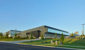Fayetteville High School metal and glass exterior surrounded by students and green landscaping