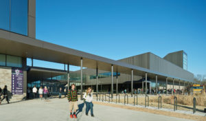 Students catching their bus after school ends seen from the front metal exterior of the building