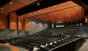 The school auditorium with towering warm wood ceilings and stone walls