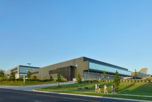 Fayetteville High School metal and glass exterior surrounded by students and green landscaping
