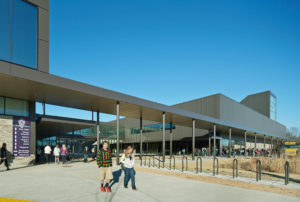 Students catching their bus after school ends seen from the front metal exterior of the building