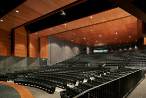 The school auditorium with towering warm wood ceilings and stone walls