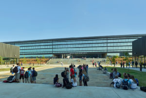 Children relaxing in the courtyard below the repeating glass windows of the library