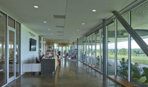 Visitor Center interior looks out through large glass windows to people in folding chairs enjoying the space