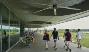 Groups of people seated under the shaded 'porch' facing the water