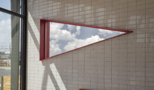 Triangular mirror with red trim mounted inside dining room