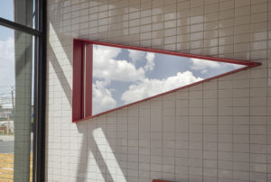 Triangular mirror with red trim mounted inside dining room