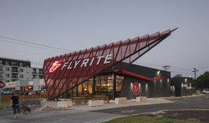 Flyrite exterior at dusk as woman and her dog walk past the property