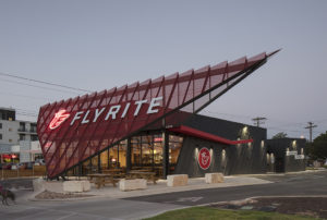 Flyrite exterior at dusk as woman and her dog walk past the property