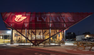 Metal screen with neon light at night with restaurant patron eating below it