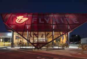 Metal screen with neon light at night with restaurant patron eating below it