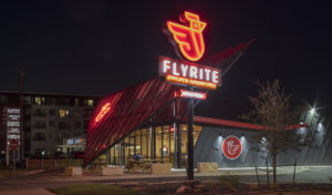 Flyrite neon sign shot at night next to the metal screen shade and restaurant structure