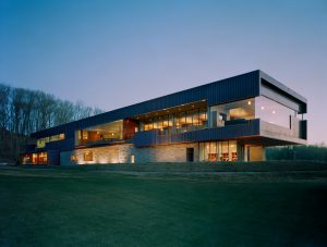 Blessings Golf Clubhouse seen at dusk lit from inside looking over the cut grass