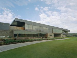 Blessings Golf Clubhouse exterior made of stone and metal next to a large grassy lawn