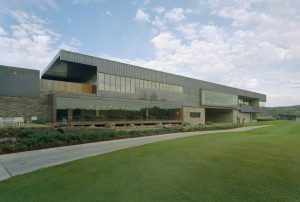 Blessings Golf Clubhouse exterior made of stone and metal next to a large grassy lawn