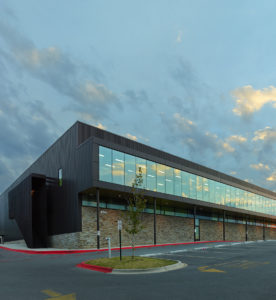 Exterior shot of the glass window walls and metal structure seen at sundown