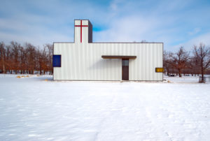 St. Nicholas Eastern Orthodox Church white exterior with red cross seen in a field of snow