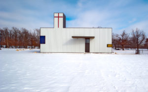St. Nicholas Eastern Orthodox Church white exterior with red cross seen in a field of snow