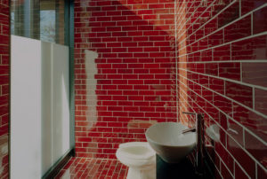 Red tile lined bathroom with natural light and opaque glass