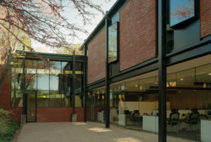 The Fulbright Building courtyard space with trees and shrubs intersecting with the brick and steel building