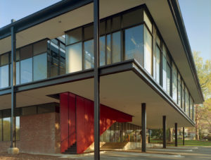 A brick and steel exterior with a red grated staircase that leads into the building from parking below