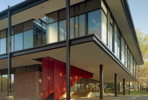 A brick and steel exterior with a red grated staircase that leads into the building from parking below