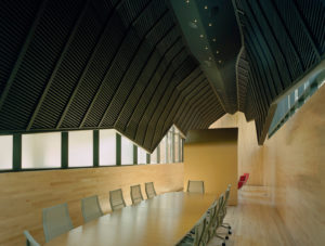 Wooden interior redesign of The Fullbright Building showcasing a ‘shroud,’ clad in black zinc, suspended above a wooden conference room