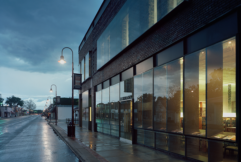 The building's exterior lit from inside at dusk during a rainstorm