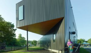 Box rib metal wall panel exterior facing the playground and a mother and daughter walk past