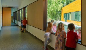 An interior hallway space with children looking at each other through the glass