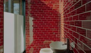 Red tile lined bathroom with natural light and opaque glass