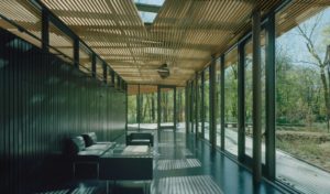 Wood slats form a semi-transparent envelope of deck, wall, and roof, supported by a steel exoskeleton, allowing light and moisture to filter through it