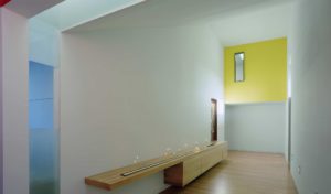 A view of a white wall and candle-lit hallway with a wood floor and yellow accent wall