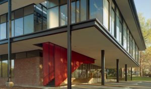 A brick and steel exterior with a red grated staircase that leads into the building from parking below