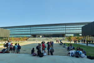 Children relaxing in the courtyard below the repeating glass windows of the library