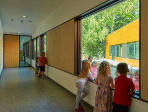 An interior hallway space with children looking at each other through the glass