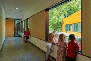 An interior hallway space with children looking at each other through the glass