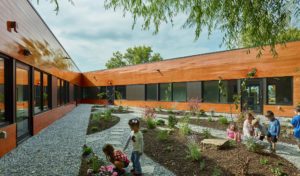 An enclosed area where children play in the garden line in cypress siding walls open to the blue sky above