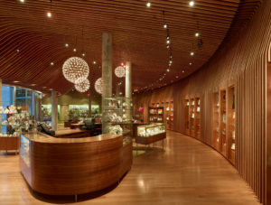 A wooden floors, walls, and ceilings look out through glass at the concrete museum