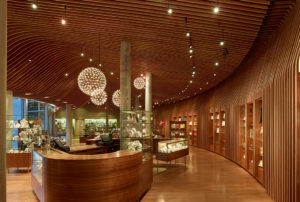 A wooden floors, walls, and ceilings look out through glass at the concrete museum