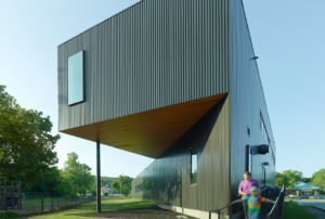 Box rib metal wall panel exterior facing the playground and a mother and daughter walk past