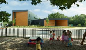 A view of the school from the play area just across the street, the silhouette of the building is surrounded by trees