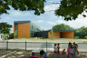 A view of the school from the play area just across the street, the silhouette of the building is surrounded by trees