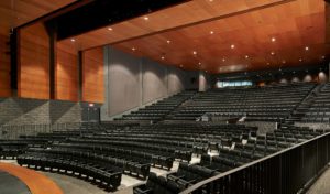 The school auditorium with towering warm wood ceilings and stone walls