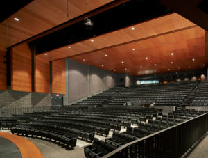 The school auditorium with towering warm wood ceilings and stone walls