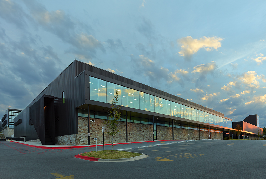 Exterior shot of the glass window walls and metal structure seen at sundown