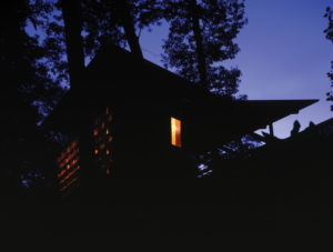 Moore HoneyHouse lit from inside at night with glowing jars of honey shining brightly through the glass