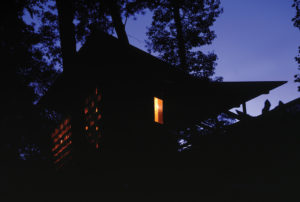 Moore HoneyHouse lit from inside at night with glowing jars of honey shining brightly through the glass