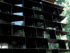 Moore HoneyHouse exterior window looking at steel plate and faceted glass load bearing wall that displays jars of honey